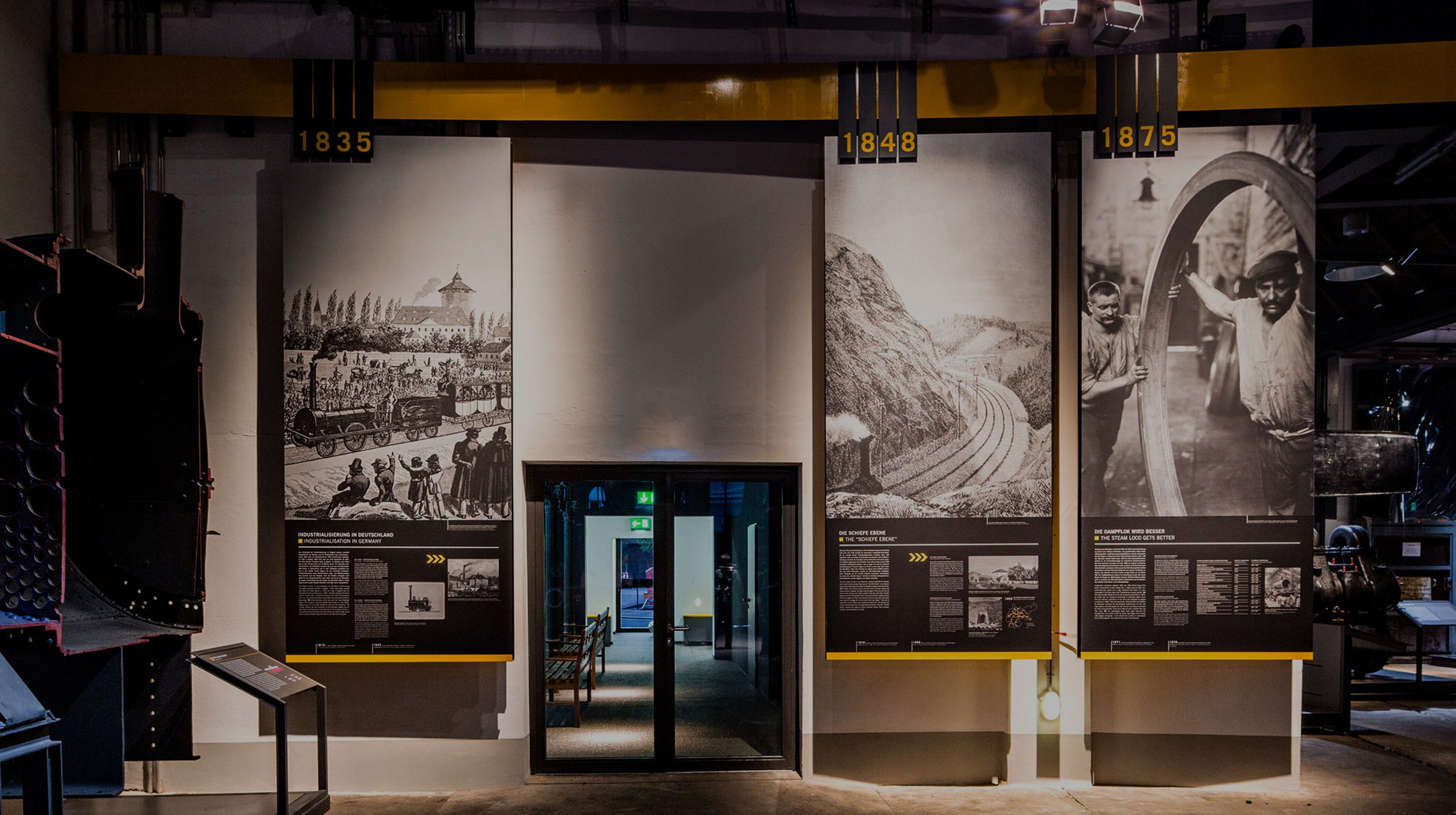 Drei große Informationstafeln über verschiedene Epochen der Eisenbahnzeit hängen im Museum